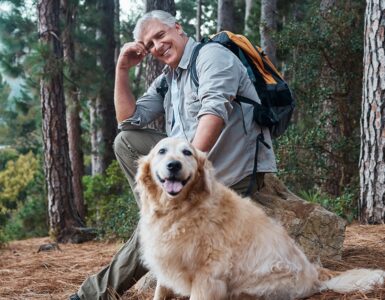 Man, hiking and happy dog outdoor in nature for exercise, fitness and trekking for health and wellness. Senior male and pet animal portrait on hike in forest for workout and cardio with backpack.