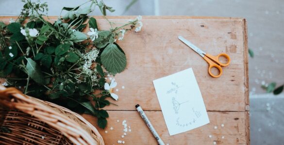 Flowers, scissors, and paper on table for arts and crafts. Best hobbies for winter on The Tonic