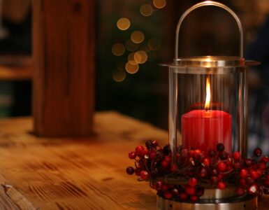 Red christmas candle in a clear candle holder surrounded by red berries. Christmas isn't the same after losing my dad on The Tonic