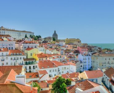 Image of the Lisbon skyline, with an assortment of colourful houses and a bright blue sky.