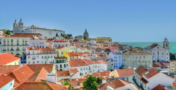 Image of the Lisbon skyline, with an assortment of colourful houses and a bright blue sky.